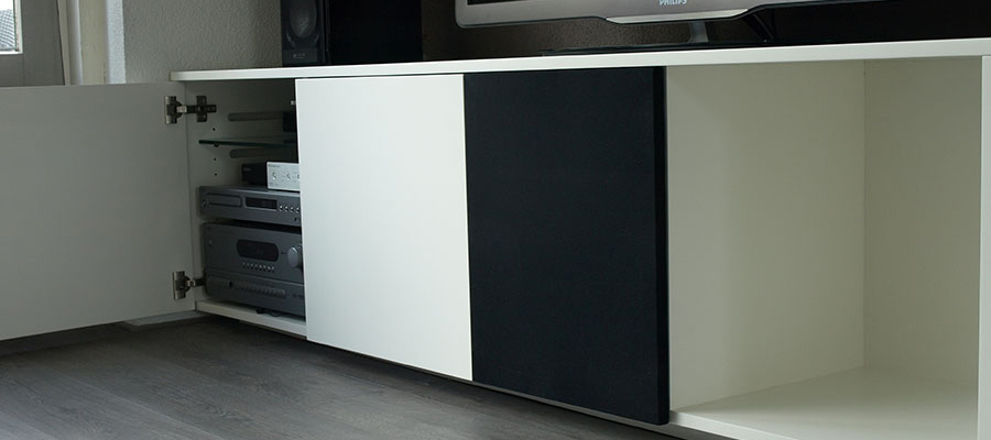 Wandmeubel met speakerdoek en daarachter een center speaker.